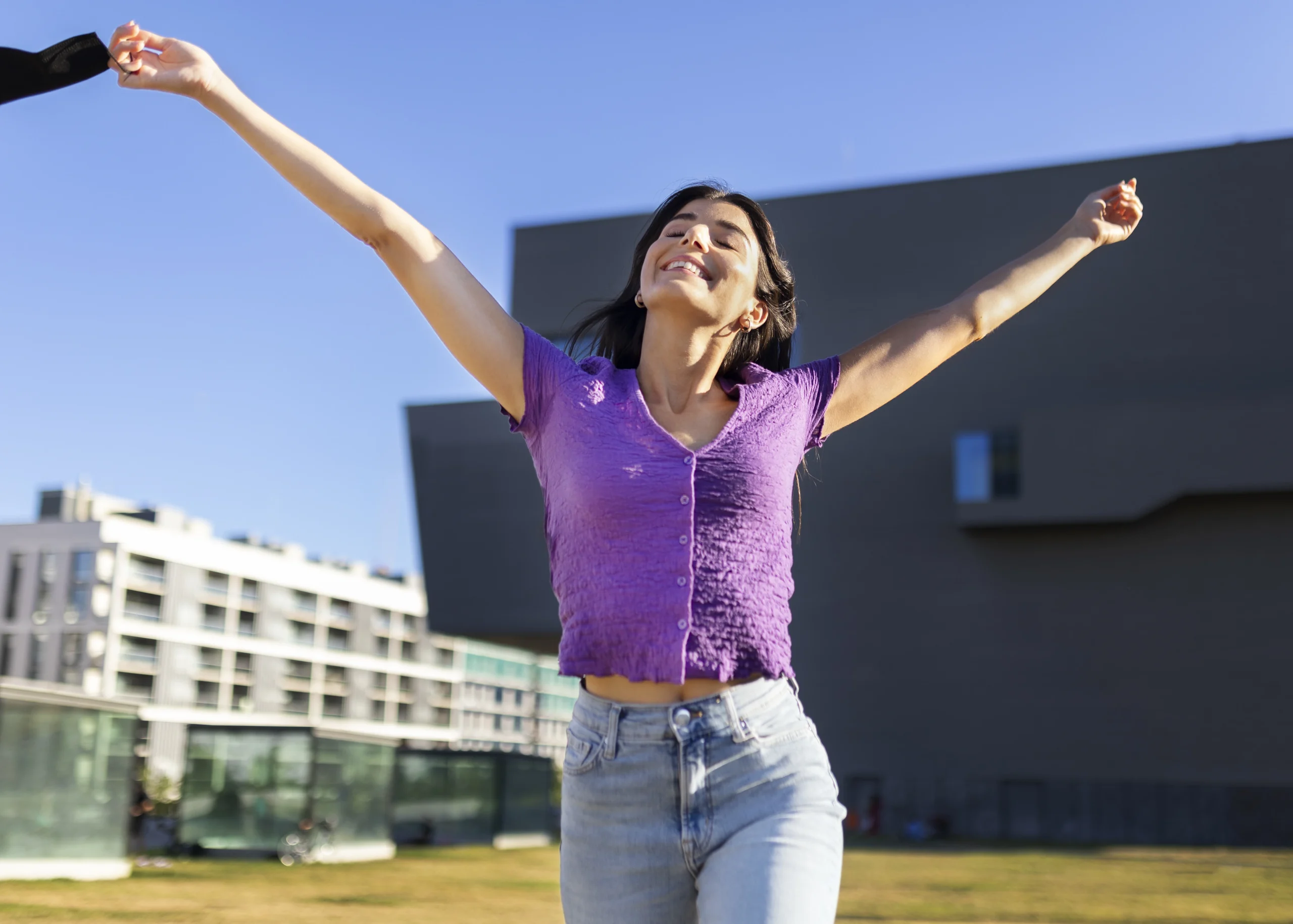 visione frontale di una giovane donna in uno scorcio cittadino con e braccia aperte e sorridente